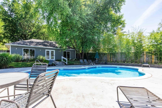 view of pool featuring french doors, a fenced in pool, fence, a patio area, and an outdoor structure