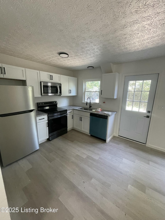5001 Wabash Pl, Louisville, KY 40214 - kitchen with white cabinetry, light wood-style flooring, and stainless steel appliances