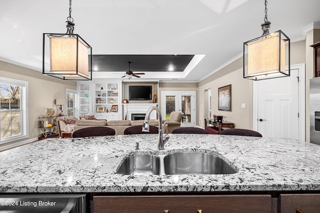 kitchen with open floor plan, ornamental molding, a sink, and a raised ceiling