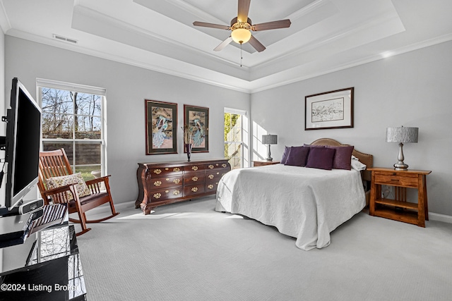 bedroom with a tray ceiling, crown molding, baseboards, visible vents, and carpet