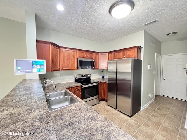 kitchen featuring brown cabinetry, appliances with stainless steel finishes, a sink, and visible vents