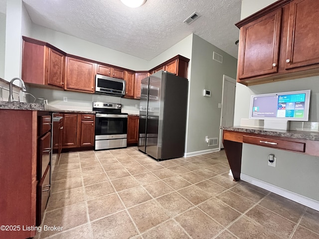 kitchen featuring baseboards, visible vents, dark stone counters, and stainless steel appliances