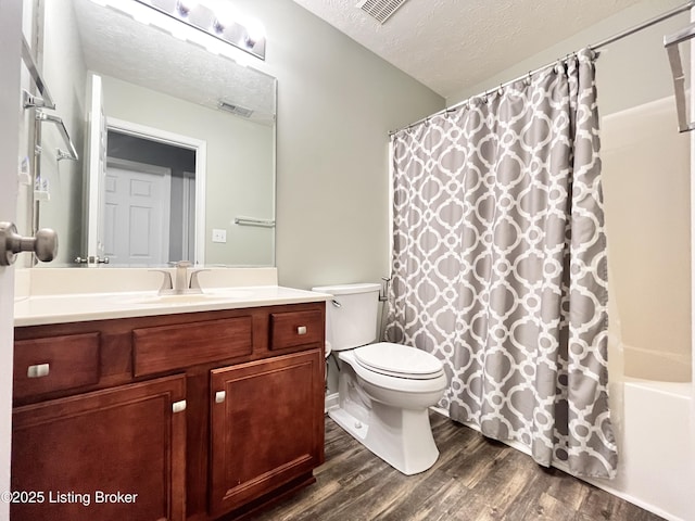 bathroom with a textured ceiling, toilet, visible vents, wood finished floors, and vanity