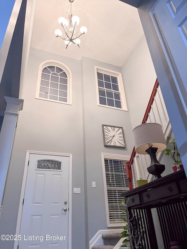 foyer with baseboards and a chandelier