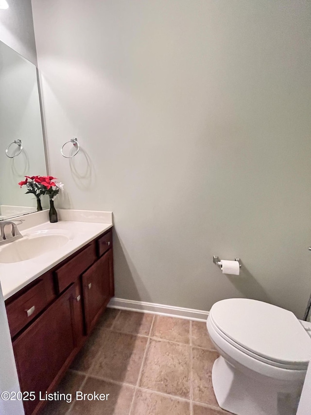 bathroom with toilet, vanity, and baseboards