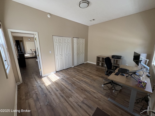 office featuring visible vents, baseboards, vaulted ceiling, and wood finished floors