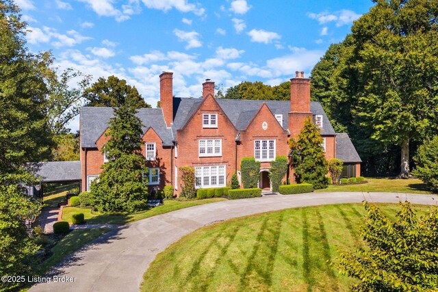 tudor house featuring curved driveway and a front lawn