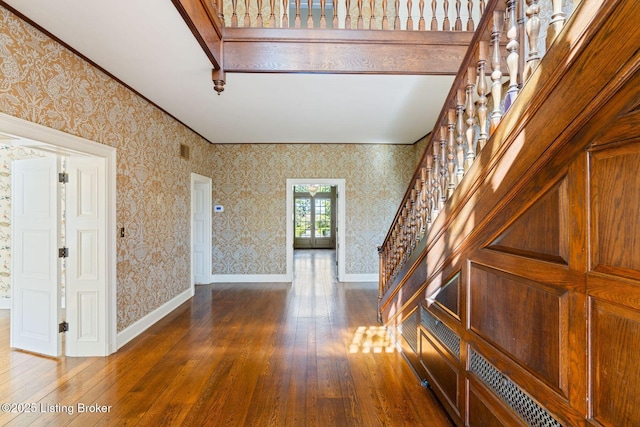 interior space featuring wood-type flooring, baseboards, stairway, and wallpapered walls