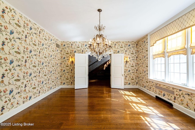 unfurnished dining area with a notable chandelier, baseboards, wallpapered walls, dark wood-style floors, and visible vents