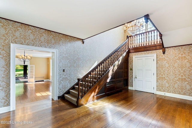 stairs with a chandelier, wallpapered walls, and hardwood / wood-style flooring