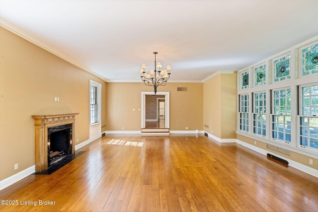unfurnished living room with baseboards, ornamental molding, a chandelier, light wood-style floors, and visible vents