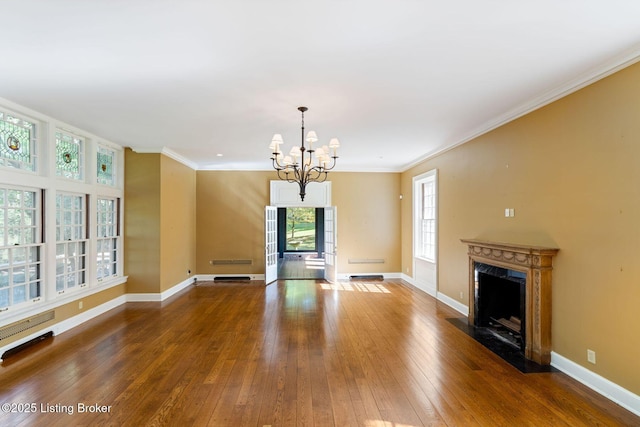 unfurnished living room with baseboards, a notable chandelier, ornamental molding, a high end fireplace, and hardwood / wood-style flooring