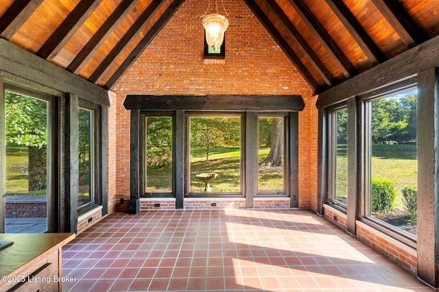 unfurnished sunroom featuring beam ceiling, tile patterned floors, high vaulted ceiling, and brick wall