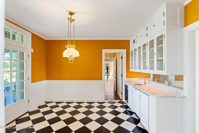 kitchen with glass insert cabinets, light countertops, crown molding, white cabinetry, and light floors