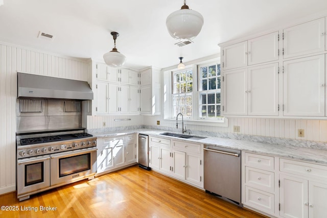 kitchen with a sink, wall chimney range hood, visible vents, and stainless steel appliances