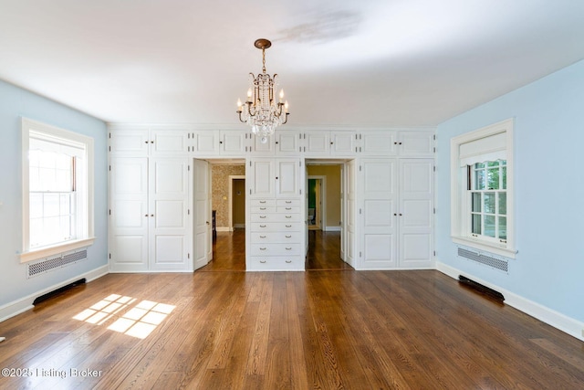 unfurnished bedroom with a closet, baseboards, a notable chandelier, and wood finished floors
