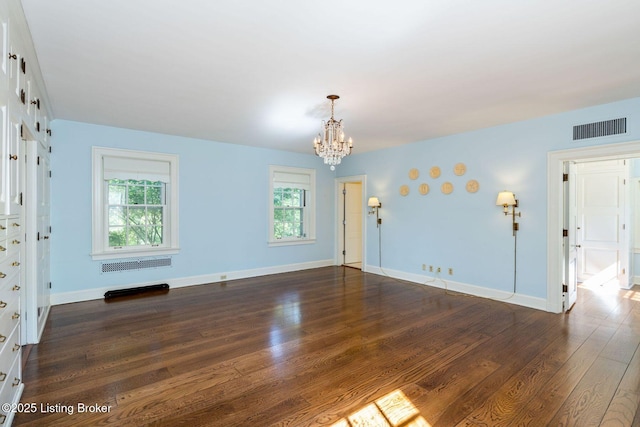 unfurnished room with a notable chandelier, visible vents, dark wood-style flooring, and baseboards