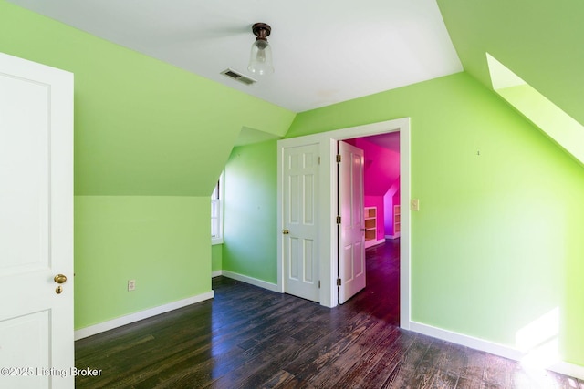 additional living space featuring visible vents, baseboards, lofted ceiling, and dark wood-style floors