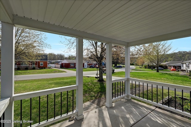 wooden terrace featuring a yard, a porch, and a residential view