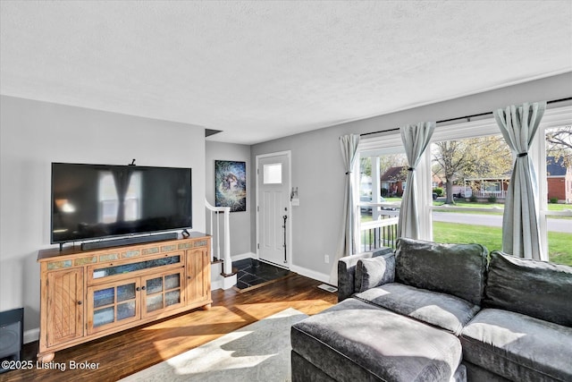 living area featuring a textured ceiling, baseboards, and wood finished floors