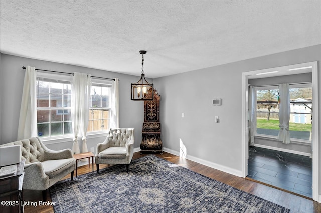 sitting room featuring dark wood-style flooring, baseboards, an inviting chandelier, and a textured ceiling