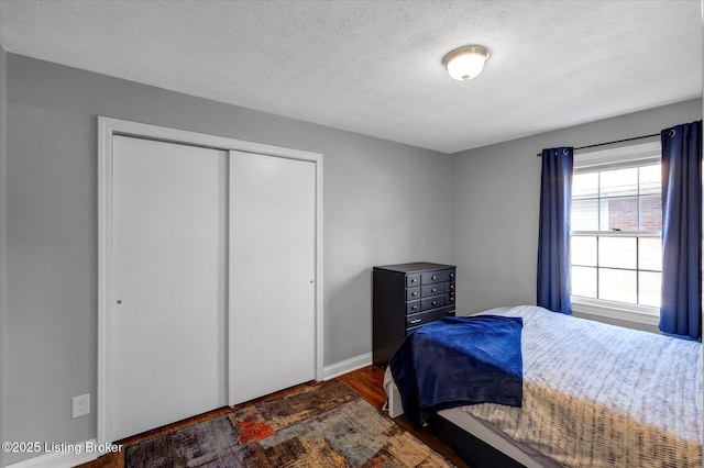 bedroom featuring a closet, a textured ceiling, baseboards, and wood finished floors