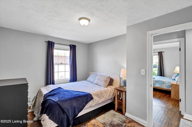 bedroom with wood finished floors, baseboards, and multiple windows