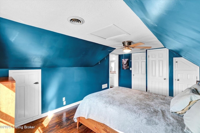 bedroom with visible vents, baseboards, a textured ceiling, vaulted ceiling, and wood finished floors