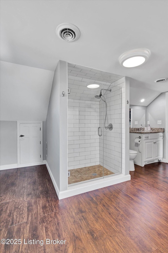 bathroom featuring visible vents, toilet, a stall shower, and wood finished floors