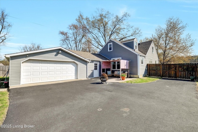 view of front of home with aphalt driveway, a garage, and fence