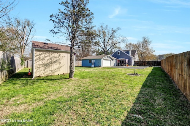 view of yard with an outbuilding, a fenced backyard, and driveway