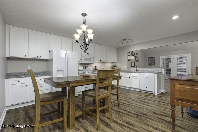 dining space featuring a notable chandelier, a textured ceiling, track lighting, recessed lighting, and dark wood-style flooring