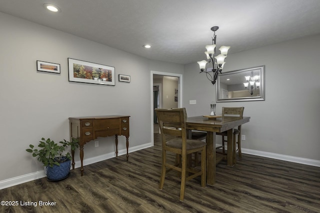 dining room featuring dark wood-style flooring, a notable chandelier, and baseboards