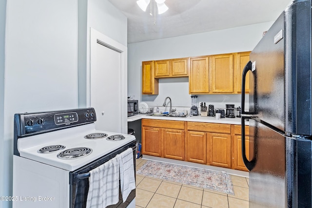 kitchen featuring a sink, light tile patterned floors, light countertops, and black appliances