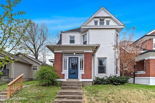 victorian-style house featuring brick siding and a front lawn