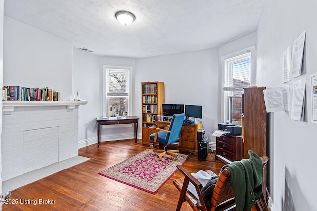 office area featuring a textured ceiling, a healthy amount of sunlight, wood finished floors, and baseboards
