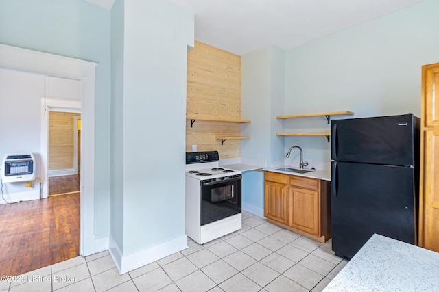 kitchen with a sink, light countertops, freestanding refrigerator, heating unit, and electric stove