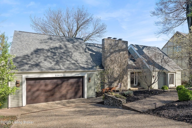 view of front facade featuring a chimney, a garage, and driveway