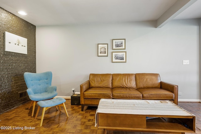 living area with visible vents, baseboards, and brick wall