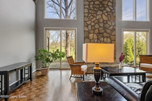sitting room featuring a wealth of natural light, a towering ceiling, and baseboards