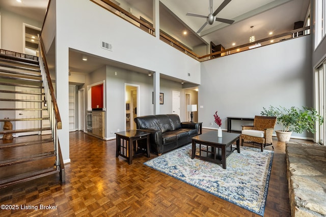 living room with ceiling fan, baseboards, visible vents, and stairway