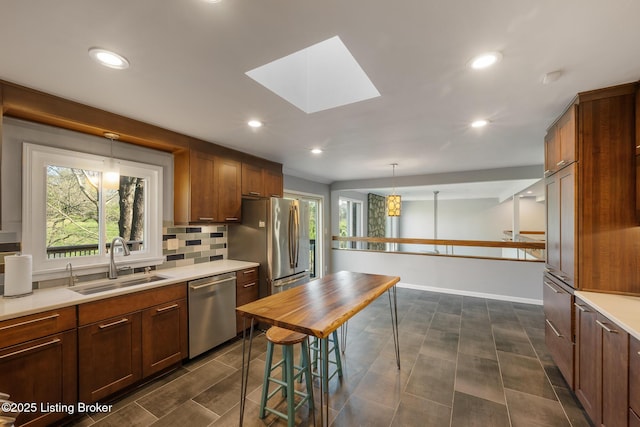 kitchen featuring stainless steel appliances, light countertops, a sink, and decorative backsplash