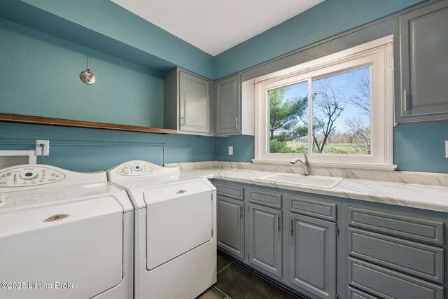 laundry area with a sink, washing machine and clothes dryer, cabinet space, and dark tile patterned floors