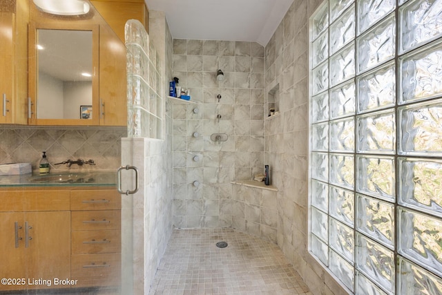 full bathroom with a tile shower and vanity