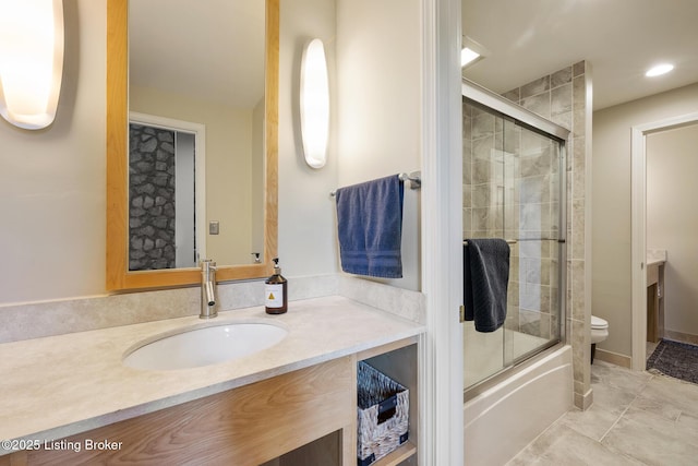 bathroom featuring combined bath / shower with glass door, vanity, and toilet
