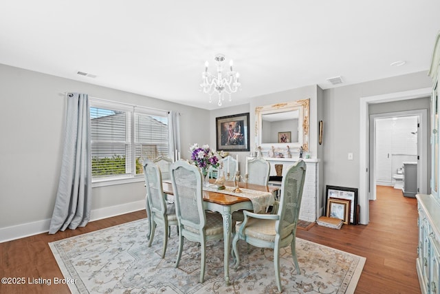 dining room featuring a chandelier, wood finished floors, baseboards, and visible vents