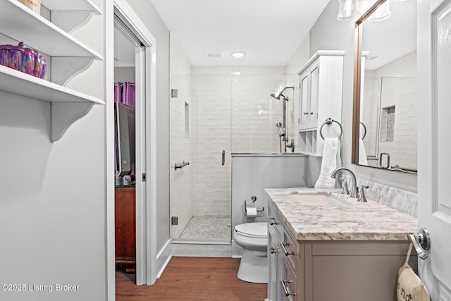 bathroom with toilet, a stall shower, wood finished floors, and vanity