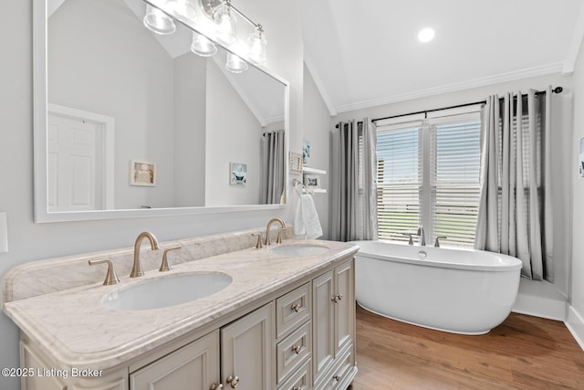full bath with double vanity, a soaking tub, a sink, and wood finished floors