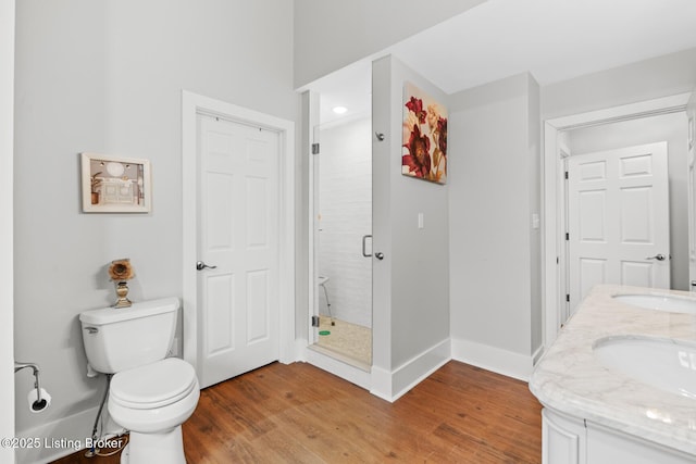 full bath featuring baseboards, a sink, toilet, a shower stall, and wood finished floors