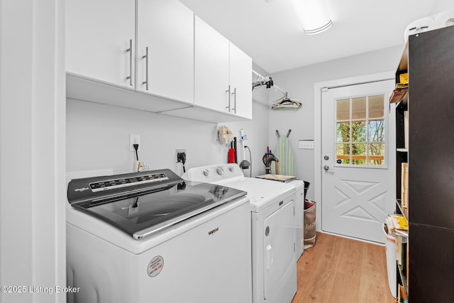 laundry room featuring cabinet space, washing machine and clothes dryer, and light wood-style flooring